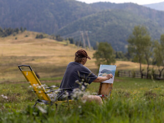 Female artist captures serene landscape in a meadow surrounded by mountains during a bright sunny day