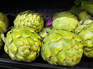 Obraz premium Fresh organic artichokes display at local grocery store supermarket.
