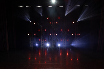 Stage illuminated with vivid blue and white lights, producing lens flares and decorative spot patterns on the floor, creating a dramatic concert or event ambiance.