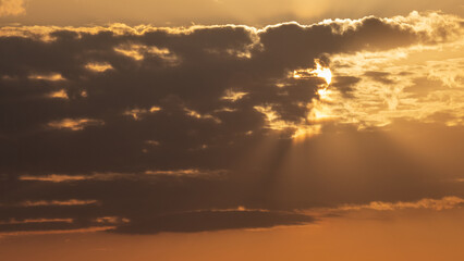 aerial view to clouds and sun behind with beams and orange colours with copy space