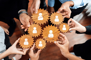 A dynamic visual of hands holding wooden gears, symbolizing teamwork and collaboration in...