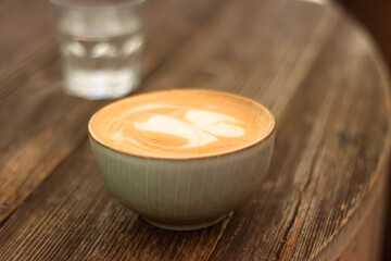 Coffee in a nice ceramic cup and glass of water on the table. Selective focus.