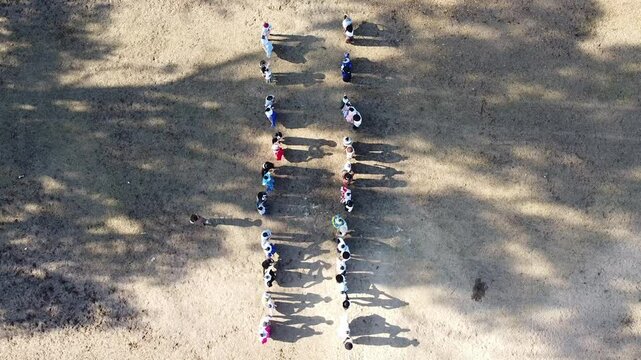 Pairs of Argentine chacarera dancers dancing in a line and gaucho riders carrying flags at the Argentine national holiday.