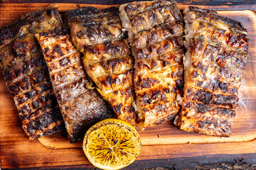 Grilled fish served on wooden board with lemon and herbs