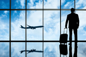Business traveler waiting at the airport as a plane flies in the distance during daytime