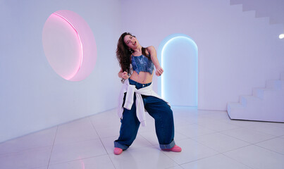 Stylish dancer performing in a modern studio with colorful lighting at night