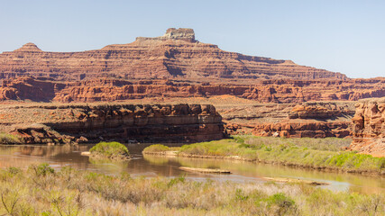 A striking view of the Colorado River carving its path through the rugged red rock formations of...