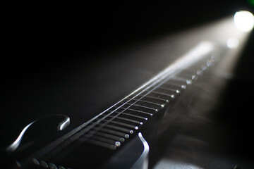 Fototapeta premium Close-up image of an unconventional electric guitar with a crossed bonesX design, black pickups at neck and bridge, non-standard string pattern Darkened background, ambient lighting casting soft sh