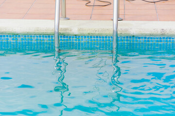detail of metal handrails entering clear pool water