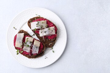 Tasty sandwiches with herring and horseradish sauce on light table, top view. Space for text