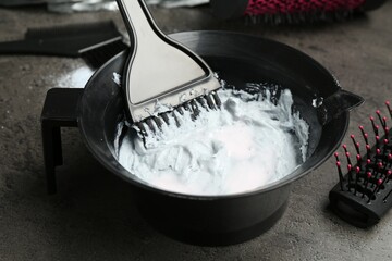 Mixing hair bleaching powder and developer on grey background, closeup