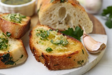 Tasty bread with garlic, herbs and oil on white table, closeup