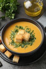 Delicious lentil cream soup served with croutons on grey table, closeup