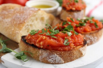 Tasty bread with tomato, parsley and oil on table, closeup
