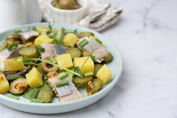 Delicious salad with herring on white marble table, closeup