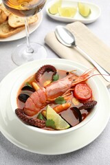 Tasty seafood soup served on light grey table, closeup