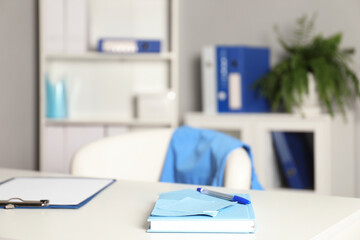 Doctor's workplace. Clipboard and other stationery on white table in medical office, closeup