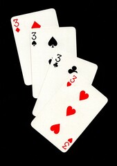 A hand of four playing cards of the same value isolated on a black background.