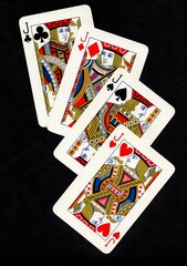 A hand of four playing cards of the same value isolated on a black background.