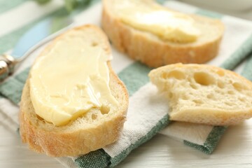 Slices of bread with butter on white wooden table, closeup