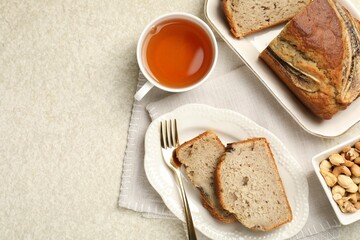 Cut banana bread with nuts and tea on light grey table, flat lay. Space for text