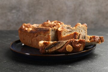 Cut banana bread with nuts on black table, closeup