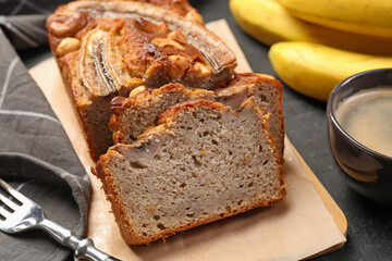 Cut banana bread with nuts and coffee on black table, closeup