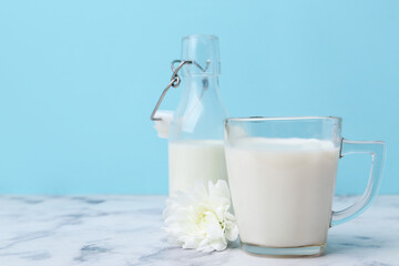 Fresh milk and flower on white marble table against light blue background