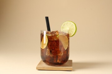 Tasty Cuba Libre cocktail in glass on beige background