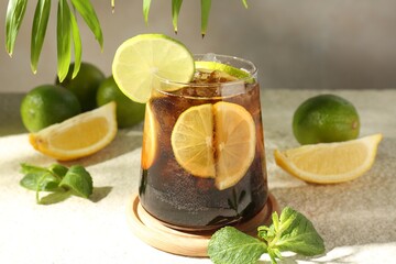 Tasty Cuba Libre cocktail in glass and ingredients on light textured table, closeup