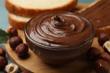 Chocolate hazelnut spread in bowl, nuts and toasts on table, closeup