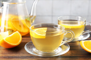 Aromatic fruit tea with orange and lemon on wooden table, closeup