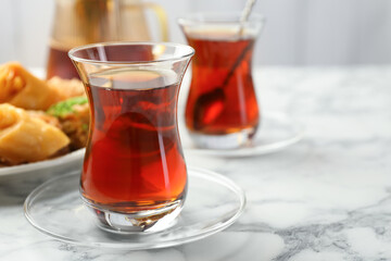 Tasty Turkish tea served with sweets on white marble table, closeup