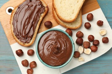 Toast with tasty chocolate hazelnut spread and nuts on blue wooden table, top view