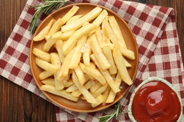 Tasty french fries served with ketchup and rosemary on wooden table, top view
