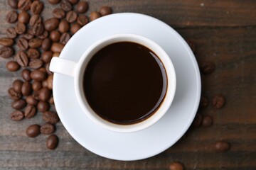 Aromatic coffee in cup and beans on wooden table, flat lay