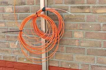 two orange fiber optic cable rolls hang outside against a stone wall