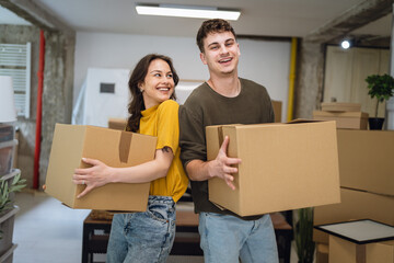 Portrait of laughing proud couple in love hold box on relocation day,