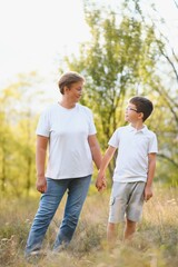 Grandmother walking with her grandson. Relaxing and joying in sunset