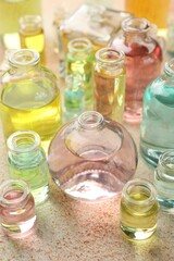 Perfume bottles with aromatic oils on beige textured background, closeup