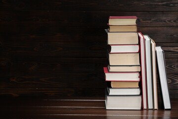Fototapeta premium Stack of old books on wooden table, space for text
