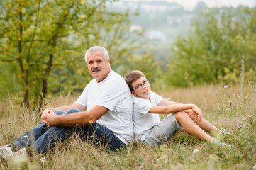 Fototapeta premium Grandfather and grandson walking at sunset