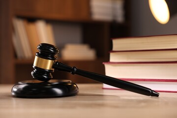 Judge's gavel and books on wooden table indoors, selective focus
