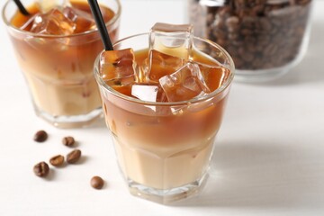 Tasty iced coffee and beans on white table, closeup