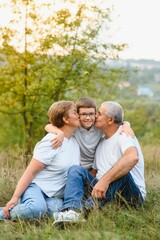 Fototapeta premium Grandparents with they grandson. They playing on meadow and joying in sunset