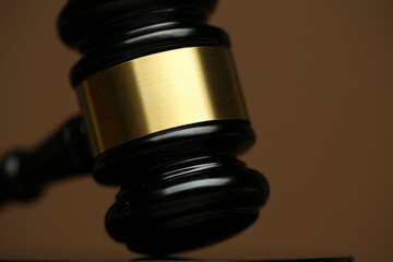 Judge's gavel on brown background, closeup view