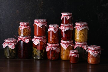 Many jars with different pickled products on wooden table