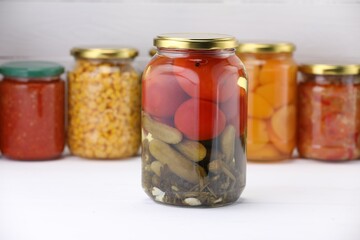 Many jars with different pickled products on white wooden table