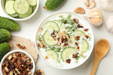 Tasty cucumber soup with dill, nuts and garlic on white table, flat lay