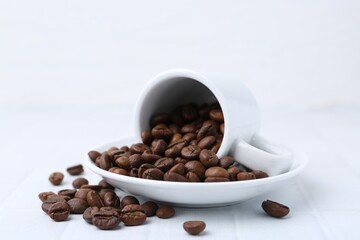 Aromatic coffee beans, cup and saucer on white table, closeup